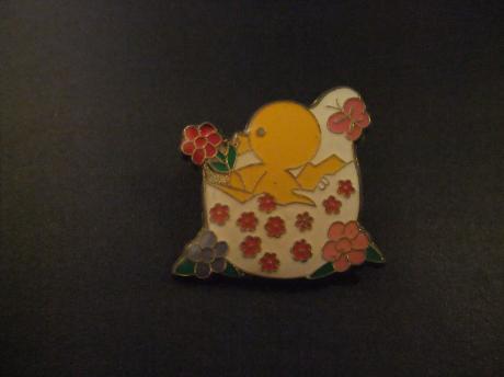 Paaskuiken kruipt uit het ei en kust de bloemen